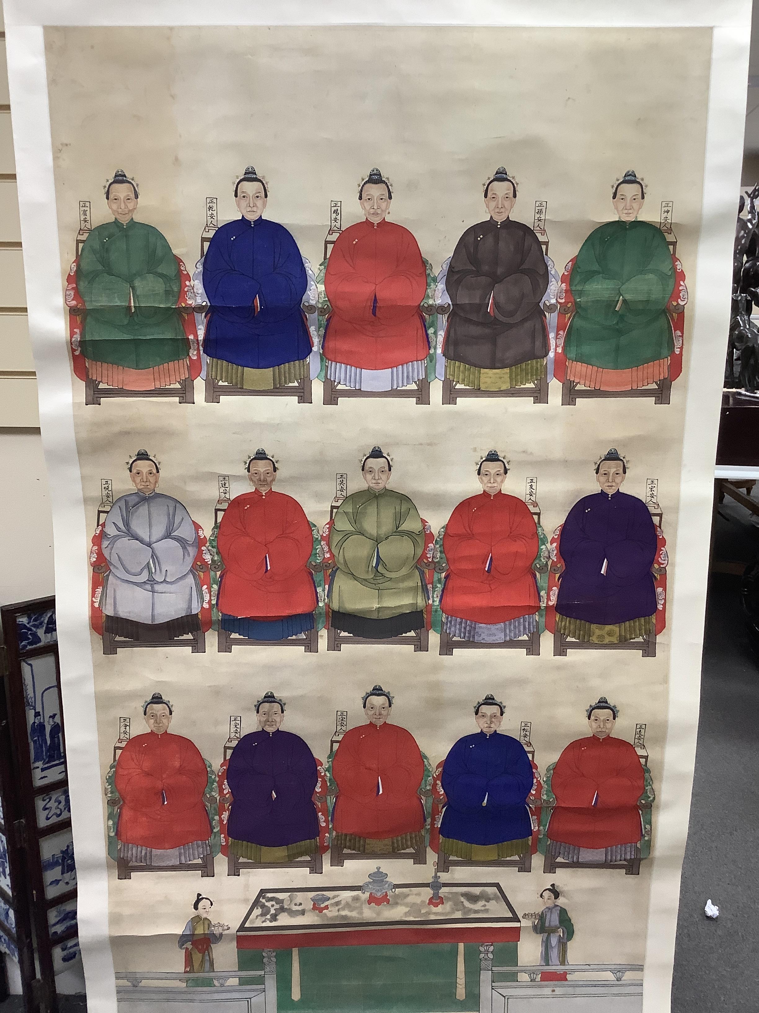 A Chinese ancestor scroll painting on paper, late Qing dynasty, depicting fifteen women seated in formal robes, with two attendants offering gifts below, Image 159cm x 91cm, later mounted